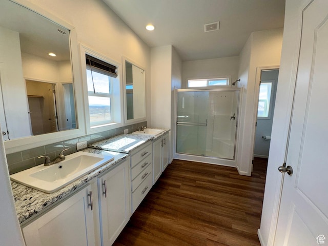 full bathroom featuring a sink, wood finished floors, visible vents, a shower stall, and double vanity