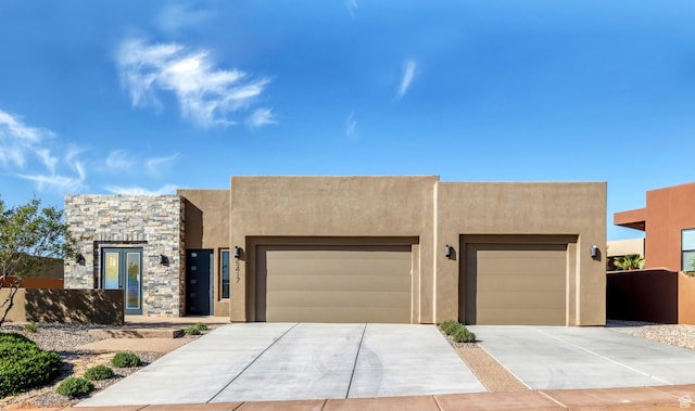 southwest-style home with stucco siding, concrete driveway, an attached garage, and stone siding