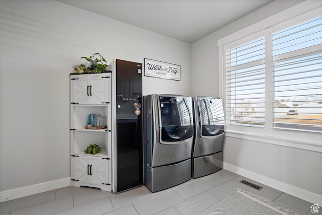 clothes washing area with laundry area, visible vents, independent washer and dryer, and baseboards