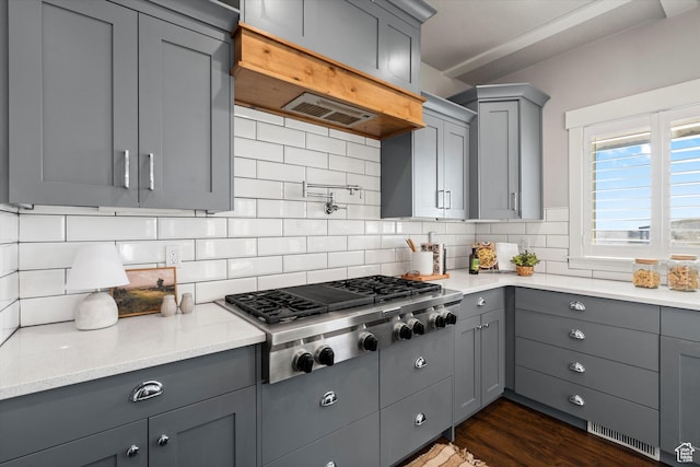 kitchen with visible vents, gray cabinets, decorative backsplash, dark wood finished floors, and stainless steel gas stovetop
