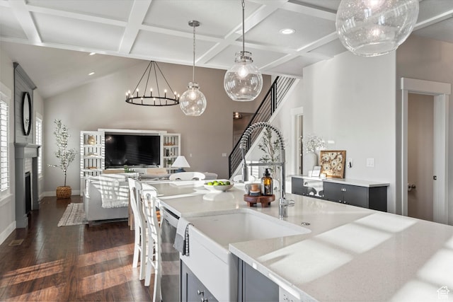 kitchen featuring stainless steel dishwasher, dark wood-type flooring, open floor plan, a large fireplace, and a sink