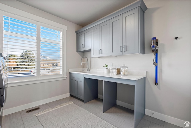clothes washing area featuring baseboards, visible vents, and a sink