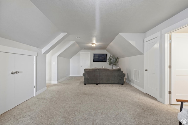 bonus room with lofted ceiling, carpet floors, a textured ceiling, and visible vents