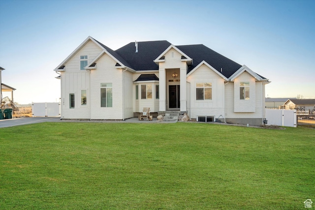 view of front of home with entry steps, fence, a gate, a front lawn, and board and batten siding
