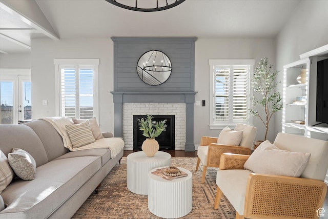 living room with lofted ceiling, a brick fireplace, and wood finished floors