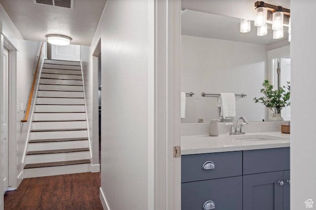 bathroom featuring baseboards, visible vents, wood finished floors, a textured ceiling, and vanity