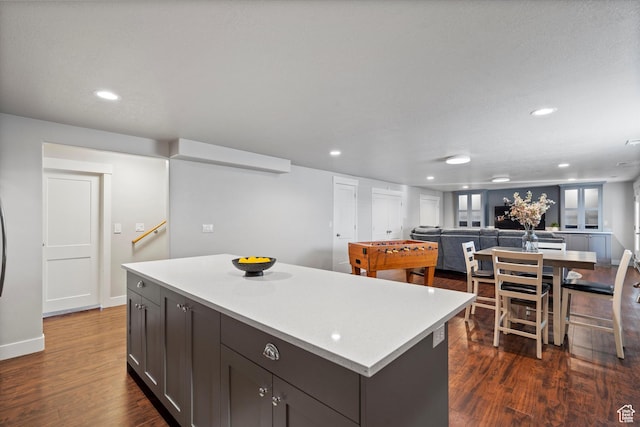 kitchen featuring baseboards, dark wood-style floors, a kitchen island, light countertops, and recessed lighting