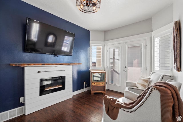 living area featuring baseboards, visible vents, a glass covered fireplace, wood finished floors, and french doors