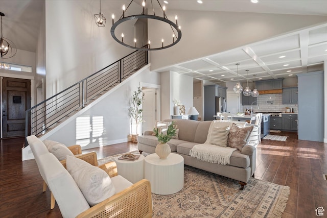 living room with a high ceiling, stairs, a chandelier, and dark wood-style flooring