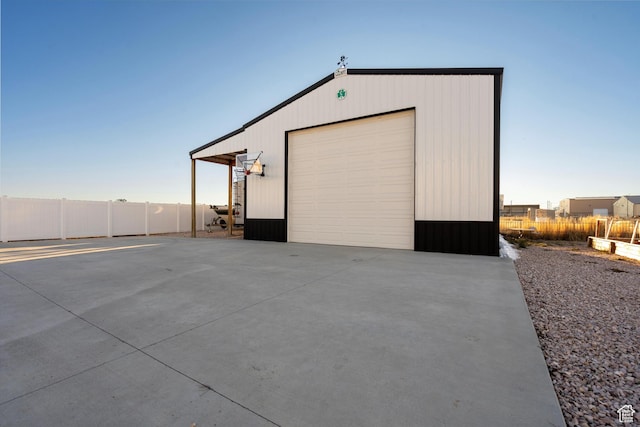 garage with concrete driveway, a detached garage, and fence