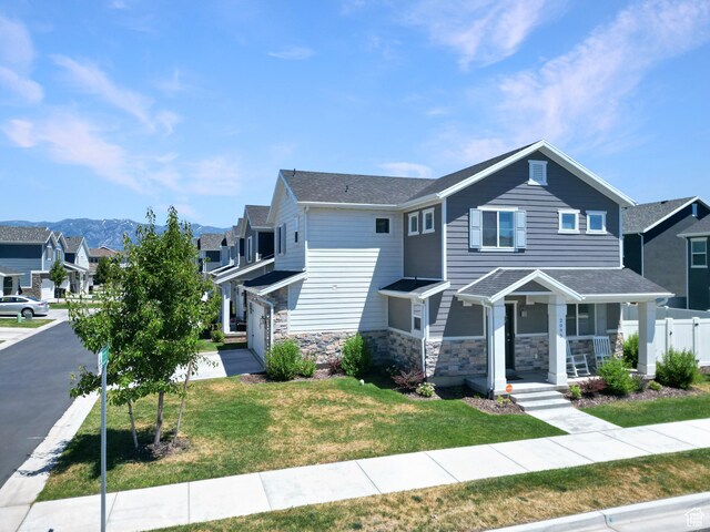 view of front of home with a porch, stone siding, a residential view, and fence