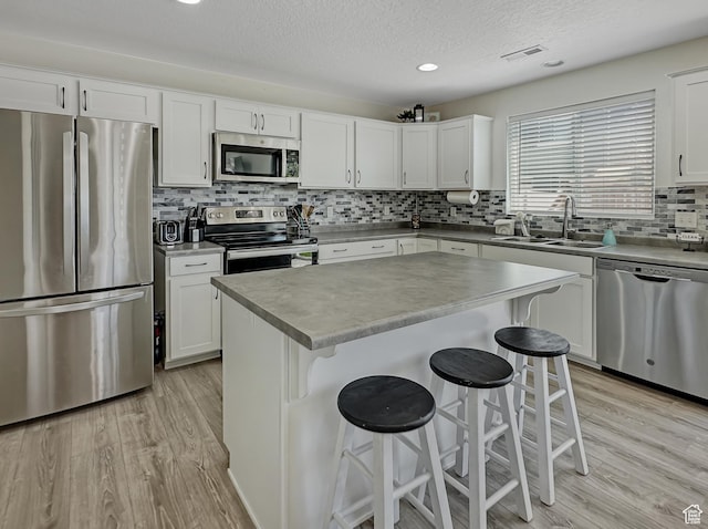 2095 W 3330 S, Syracuse, UT 84075 - kitchen with stainless steel appliances, a sink, light wood-type flooring, a kitchen bar, and a textured ceiling