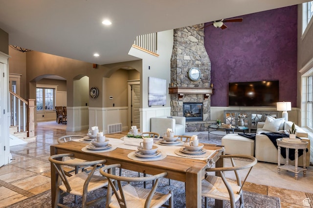 14794 S Vintage View Ln, Draper, UT 84020 - dining room featuring arched walkways, a stone fireplace, visible vents, stairs, and wainscoting