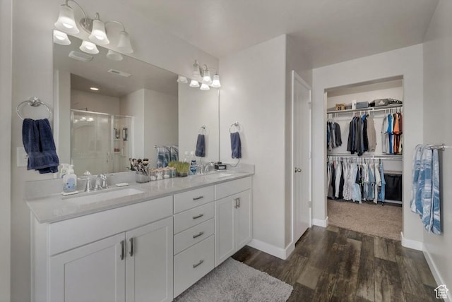 721 S Jubilee Dr, Saratoga Springs, UT 84045 - bathroom featuring wood finished floors, a sink, a shower stall, double vanity, and a walk in closet