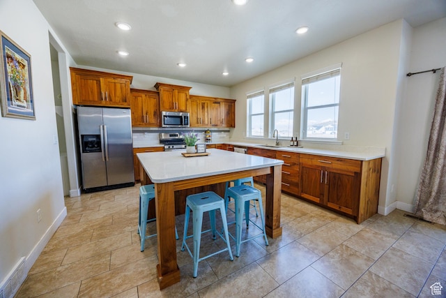 7912 N Secretariat Rd, Eagle Mountain, UT 84005 - kitchen with visible vents, a breakfast bar, a sink, stainless steel appliances, and light countertops