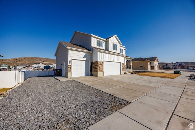 7912 N Secretariat Rd, Eagle Mountain, UT 84005 - view of home's exterior with board and batten siding, an attached garage, fence, driveway, and a mountain view