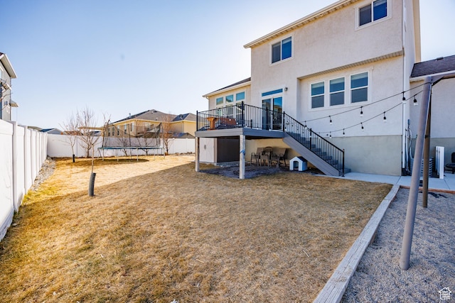 7912 N Secretariat Rd, Eagle Mountain, UT 84005 - rear view of house with stairway, a wooden deck, a fenced backyard, stucco siding, and a trampoline