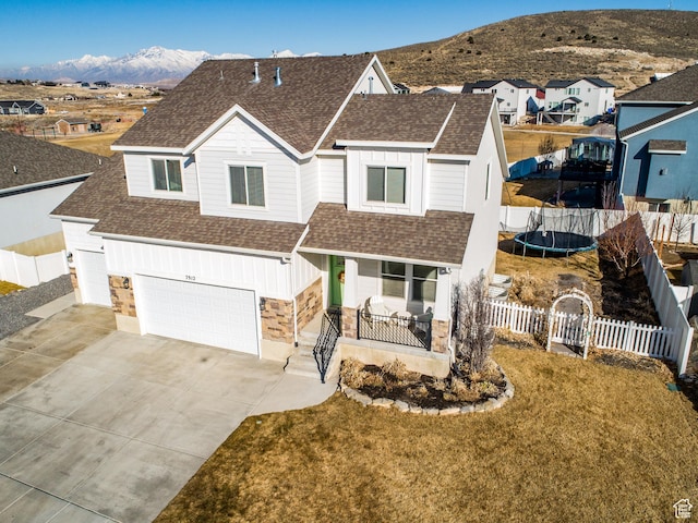7912 N Secretariat Rd, Eagle Mountain, UT 84005 - view of front facade with board and batten siding, a shingled roof, a trampoline, fence, and covered porch