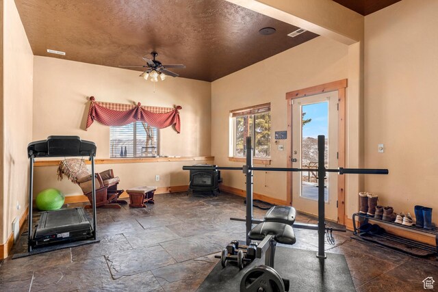 3478 E Porcupine Cir, Garden City, UT 84028 - workout room featuring stone tile floors, a ceiling fan, baseboards, and a wood stove