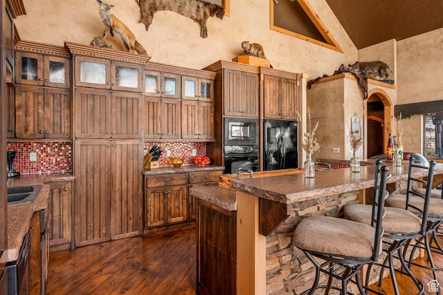 3478 E Porcupine Cir, Garden City, UT 84028 - kitchen featuring dark wood finished floors, decorative backsplash, black appliances, and a breakfast bar