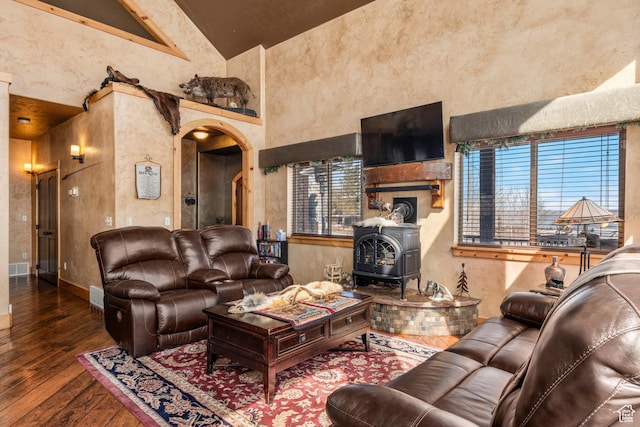 3478 E Porcupine Cir, Garden City, UT 84028 - living area featuring hardwood / wood-style floors, arched walkways, baseboards, a towering ceiling, and a wood stove