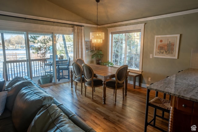 dining area featuring wood finished floors, crown molding, lofted ceiling, and a wealth of natural light