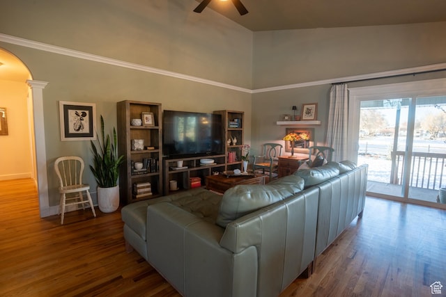 living area featuring decorative columns, wood finished floors, arched walkways, and ceiling fan