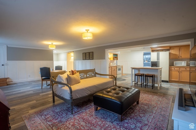 living area with wainscoting, wood finished floors, and ornamental molding