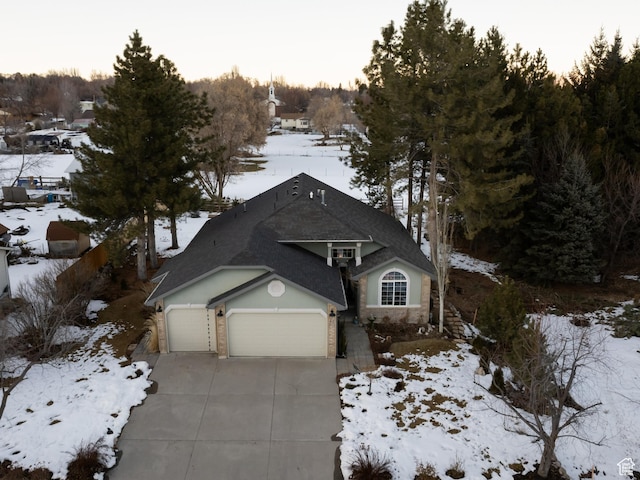 view of front of property with driveway, an attached garage, and roof with shingles