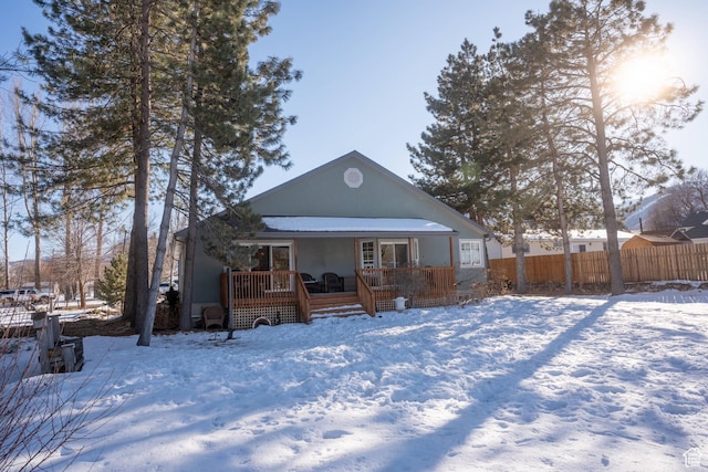 snow covered property featuring covered porch and fence
