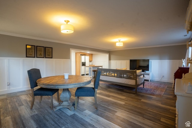 dining area with wainscoting, crown molding, and wood finished floors
