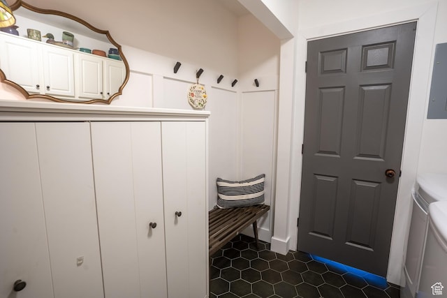 mudroom with a decorative wall, dark tile patterned floors, and electric panel