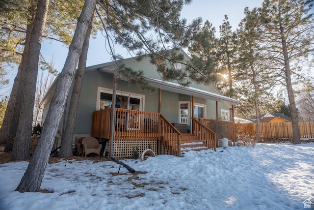 view of front of house featuring fence, stucco siding, and a porch