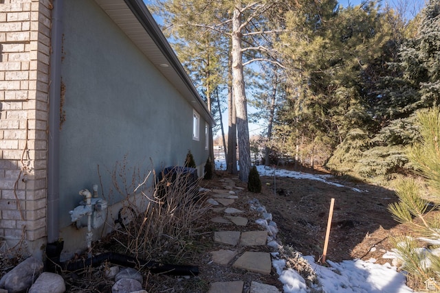 view of side of property featuring stucco siding and brick siding