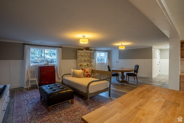 living area featuring a wainscoted wall, ornamental molding, and wood finished floors