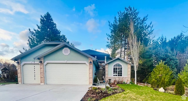ranch-style home featuring an attached garage, concrete driveway, a front yard, brick siding, and stucco siding