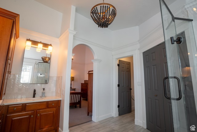 bathroom with an inviting chandelier, decorative columns, decorative backsplash, connected bathroom, and a stall shower