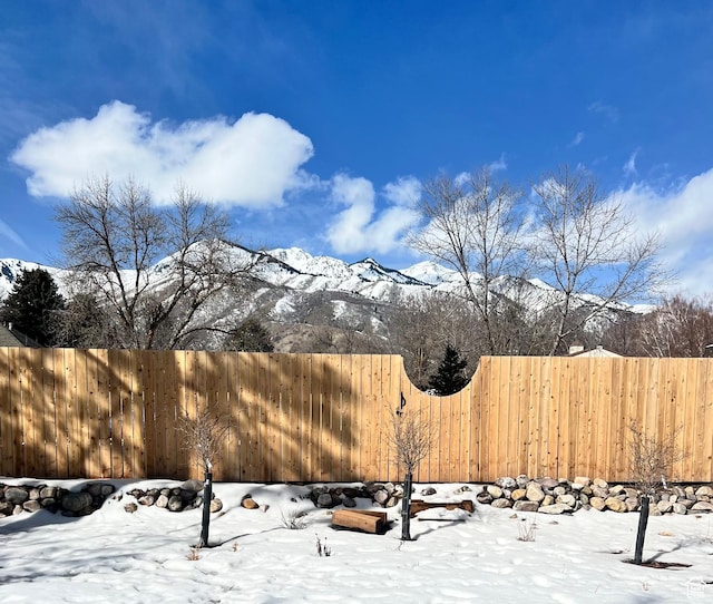 yard layered in snow featuring fence and a mountain view