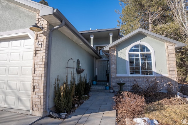 property entrance featuring stucco siding, a garage, and stone siding