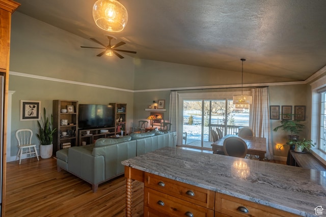 kitchen featuring a healthy amount of sunlight, lofted ceiling, ceiling fan, brown cabinetry, and wood finished floors