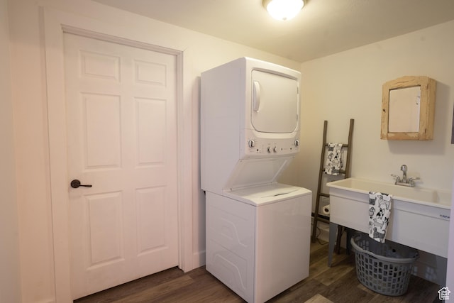 laundry room with dark wood finished floors, stacked washer and clothes dryer, and laundry area