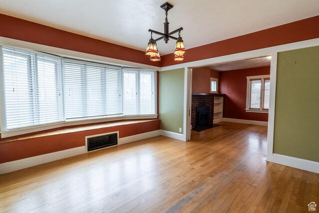429 W Center St, Logan, UT 84321 - unfurnished living room featuring hardwood / wood-style flooring, baseboards, visible vents, and a fireplace with flush hearth