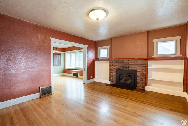 429 W Center St, Logan, UT 84321 - unfurnished living room featuring a textured ceiling, a textured wall, wood finished floors, visible vents, and a brick fireplace