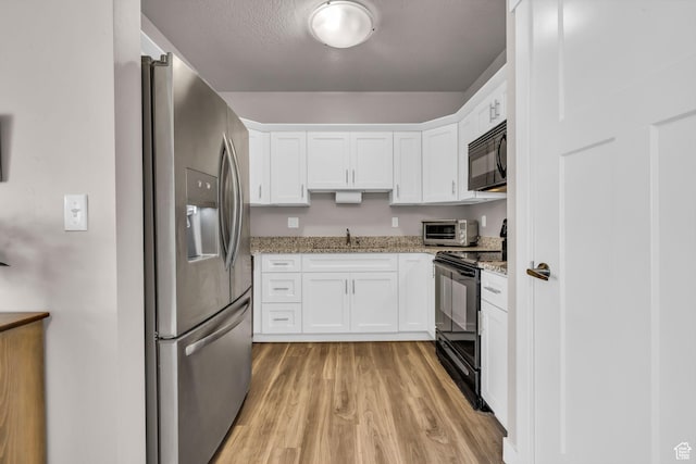1051 S 500 E Unit E203, Heber City, UT 84032 - kitchen with light stone counters, a sink, white cabinets, light wood-type flooring, and black appliances