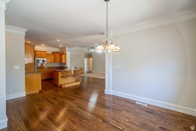 1986 Dove Dr, Santa Clara, UT 84765 - kitchen with dark wood finished floors, ornamental molding, stainless steel microwave, a breakfast bar area, and open floor plan