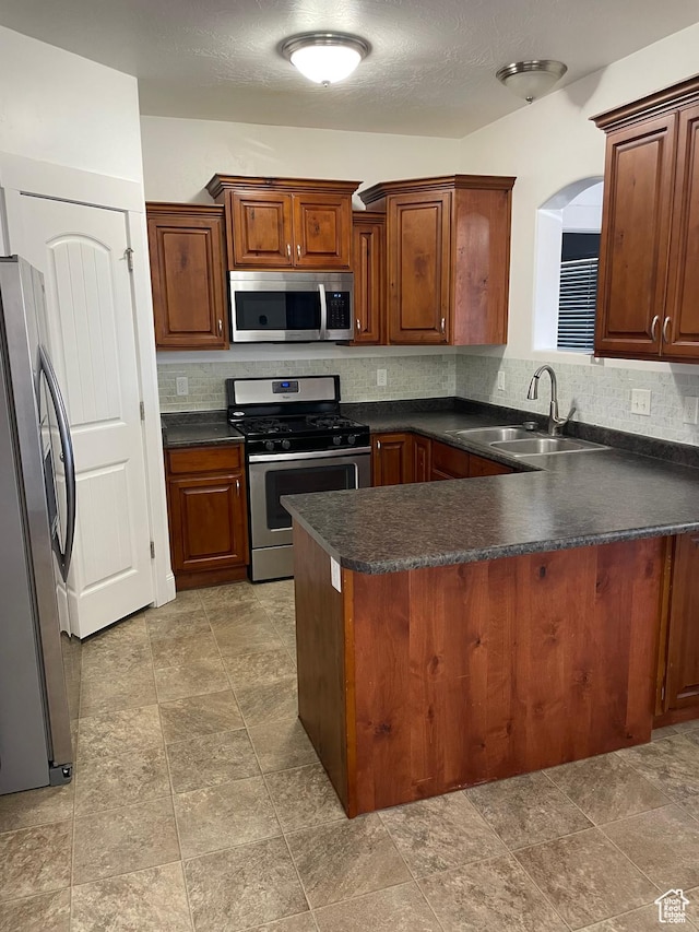 3723 E Rock Creek Rd Unit 7, Eagle Mountain, UT 84005 - kitchen featuring tasteful backsplash, dark countertops, a peninsula, stainless steel appliances, and a sink