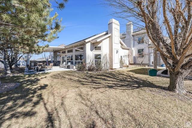 6067 S 3950 W, Roy, UT 84067 - rear view of property featuring a yard, a patio, a chimney, and stucco siding