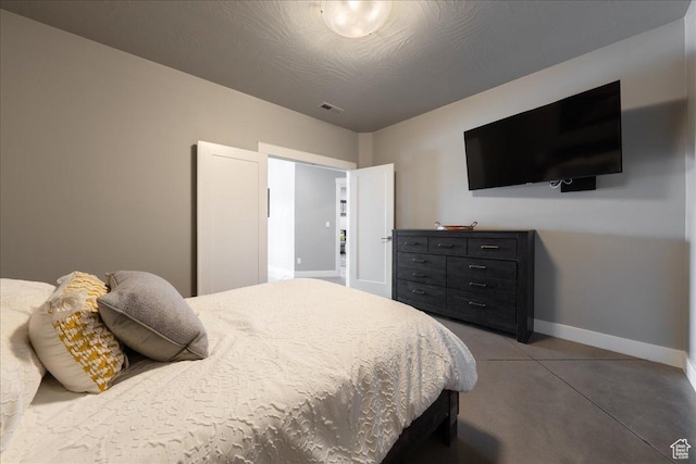 bedroom with a textured ceiling, visible vents, and baseboards