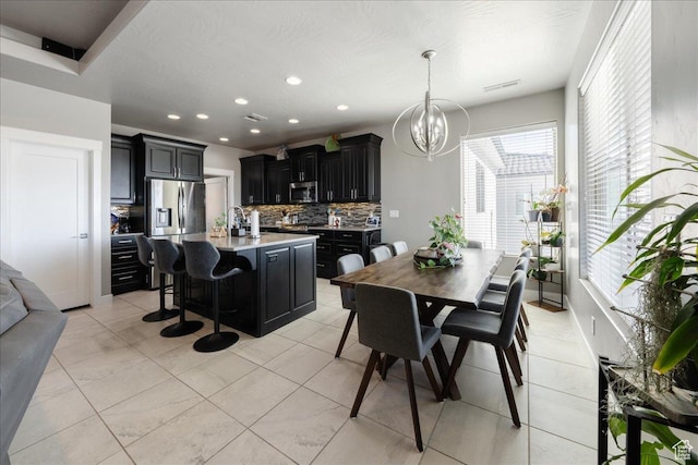 kitchen featuring appliances with stainless steel finishes, dark cabinets, an inviting chandelier, light countertops, and backsplash