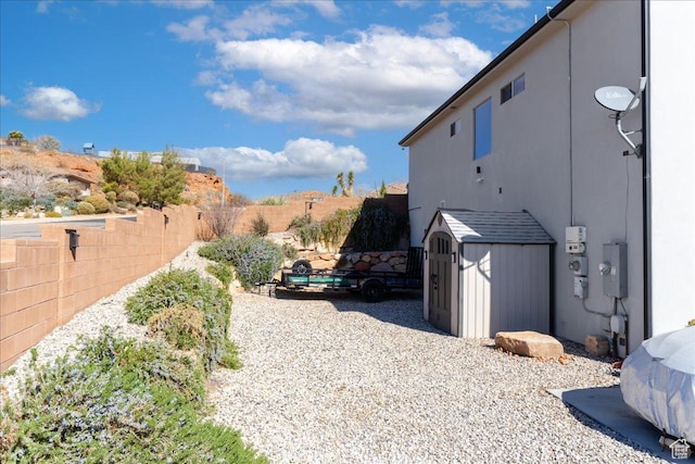 view of side of property featuring a fenced backyard, an outdoor structure, and a storage unit